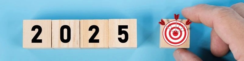 Wooden blocks displaying 2025 next to a hand holding a block with a target and arrows in the bullseye